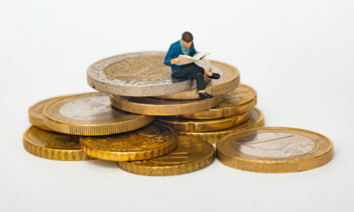 Small male figure sitting in a pile of euro coins